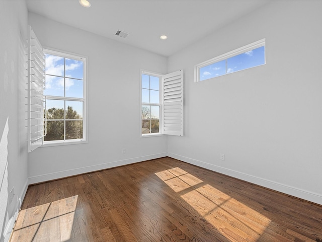 spare room featuring dark wood-type flooring and a healthy amount of sunlight