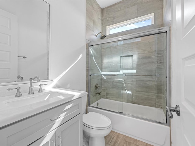 full bathroom featuring toilet, vanity, wood-type flooring, and shower / bath combination with glass door