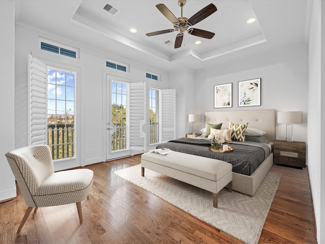 bedroom featuring ceiling fan, dark hardwood / wood-style flooring, access to outside, and a tray ceiling