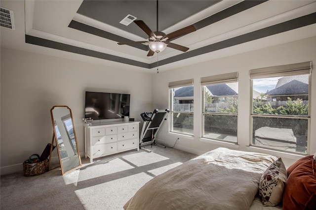 carpeted bedroom featuring a tray ceiling and ceiling fan