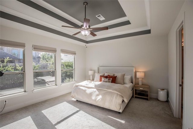 bedroom with carpet, a tray ceiling, and ceiling fan