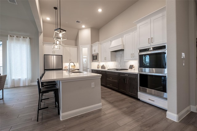 kitchen featuring a sink, visible vents, appliances with stainless steel finishes, backsplash, and custom exhaust hood