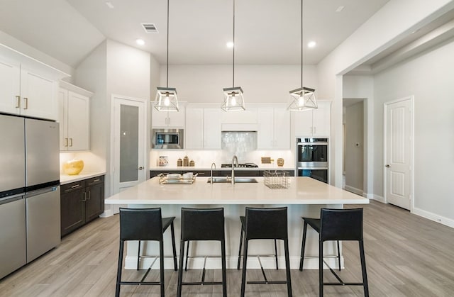 kitchen featuring visible vents, a high ceiling, appliances with stainless steel finishes, and a kitchen breakfast bar