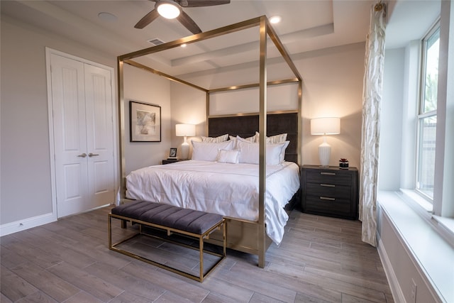 bedroom featuring a tray ceiling, a closet, visible vents, and light wood-style flooring