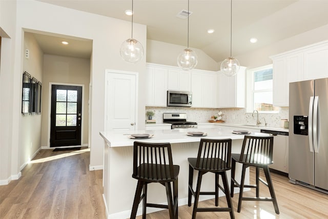 kitchen featuring sink, decorative light fixtures, a kitchen island, white cabinetry, and stainless steel appliances