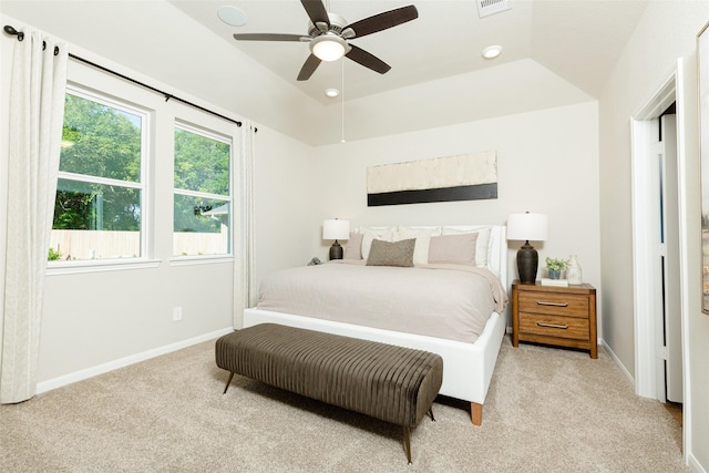 bedroom with light colored carpet, a raised ceiling, and ceiling fan