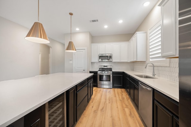 kitchen with white cabinetry, sink, beverage cooler, hanging light fixtures, and appliances with stainless steel finishes