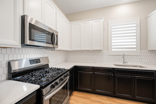 kitchen featuring white cabinets, sink, decorative backsplash, light hardwood / wood-style floors, and stainless steel appliances