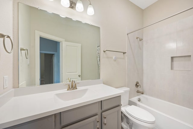 full bathroom featuring vanity, tiled shower / bath combo, and toilet