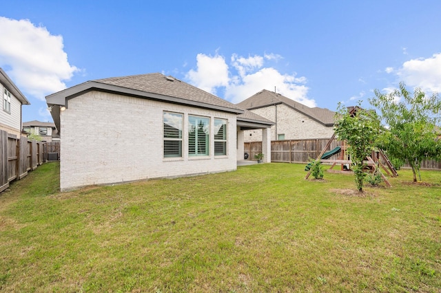 rear view of house with a yard and a playground