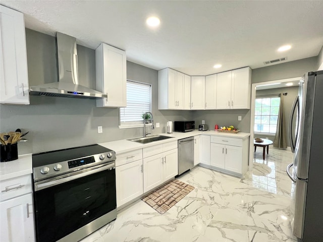 kitchen with stainless steel appliances, white cabinetry, and wall chimney exhaust hood