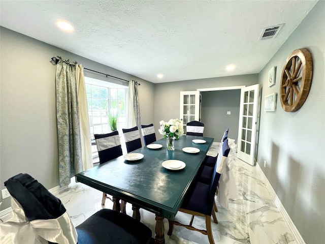 dining area with a textured ceiling and french doors