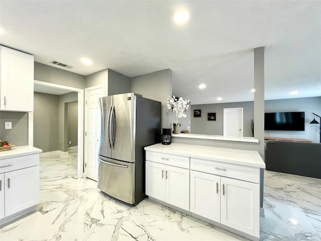 kitchen featuring stainless steel fridge, white cabinetry, and kitchen peninsula