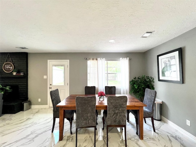 dining space with a textured ceiling and a brick fireplace