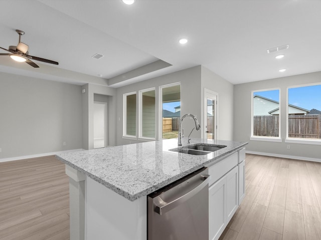 kitchen with light hardwood / wood-style flooring, light stone counters, white cabinets, stainless steel dishwasher, and sink