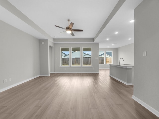 unfurnished living room featuring sink, ceiling fan, and light hardwood / wood-style flooring