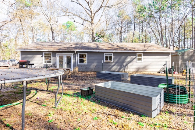 rear view of property featuring a trampoline and french doors