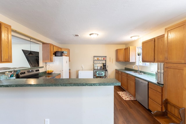 kitchen with appliances with stainless steel finishes, sink, a textured ceiling, and dark hardwood / wood-style flooring