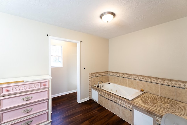 bathroom featuring hardwood / wood-style floors, tiled bath, and a textured ceiling