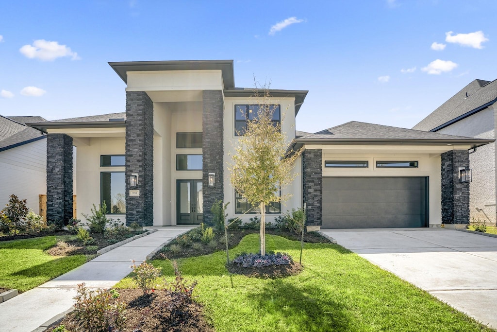 view of front of house featuring a garage, driveway, roof with shingles, stucco siding, and a front yard