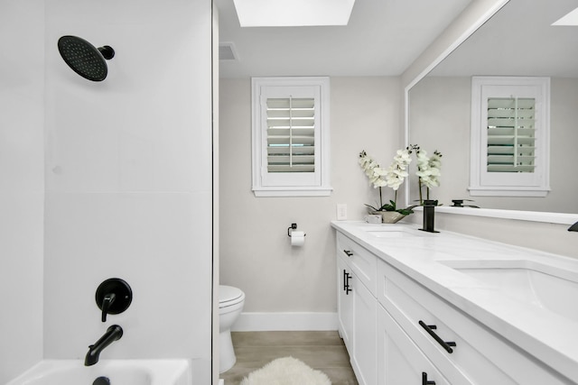 full bathroom featuring a skylight, vanity, shower / bathtub combination, and toilet