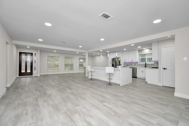 kitchen with tasteful backsplash, a breakfast bar, stainless steel appliances, white cabinets, and a kitchen island