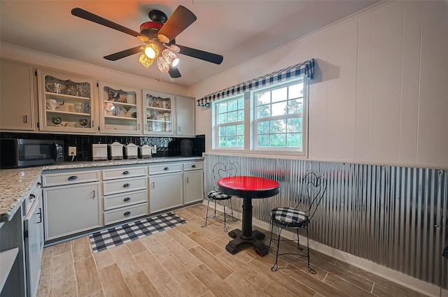 kitchen with light stone counters, ceiling fan, crown molding, light hardwood / wood-style flooring, and white cabinets