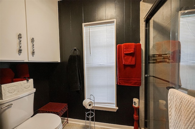 bathroom with a wealth of natural light, tile patterned floors, toilet, and walk in shower