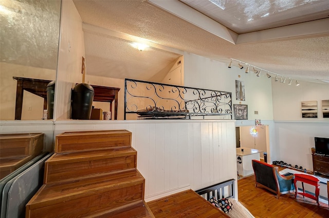 staircase with lofted ceiling, hardwood / wood-style floors, and a textured ceiling