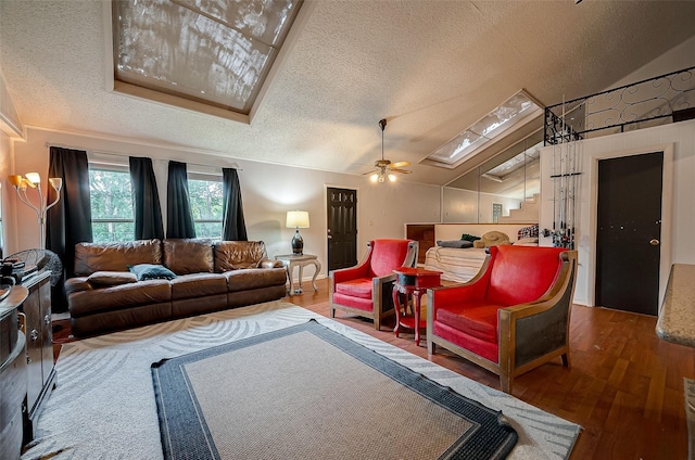 living room with a textured ceiling, hardwood / wood-style flooring, ceiling fan, and lofted ceiling