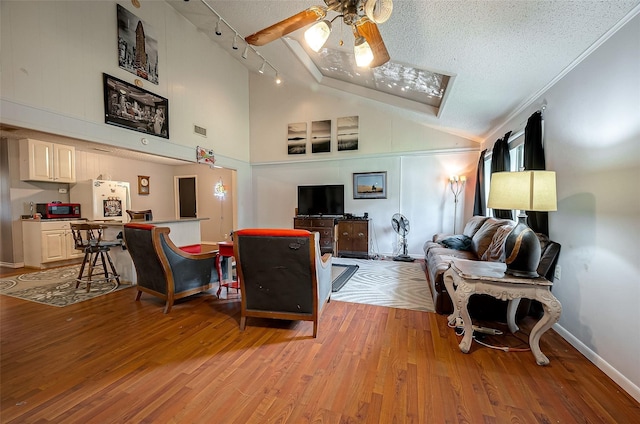 living room featuring ceiling fan, rail lighting, light hardwood / wood-style flooring, high vaulted ceiling, and a textured ceiling