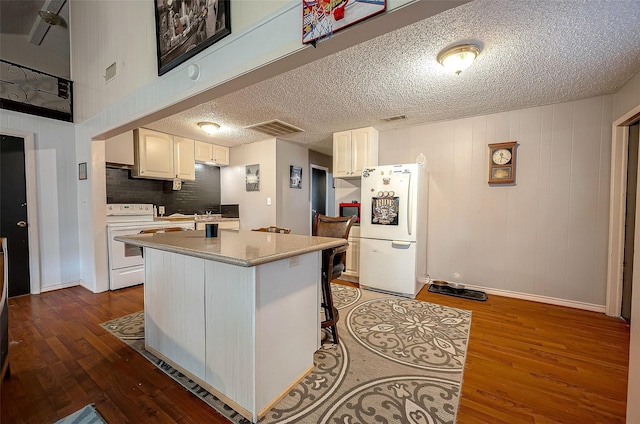 kitchen with white cabinets, a kitchen island, dark hardwood / wood-style flooring, and white appliances