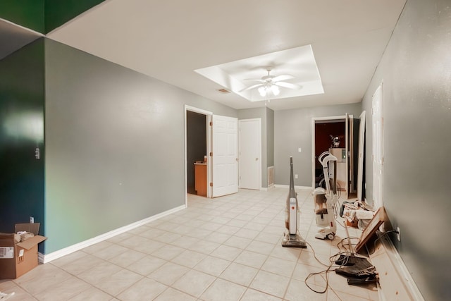 tiled spare room featuring a tray ceiling and ceiling fan