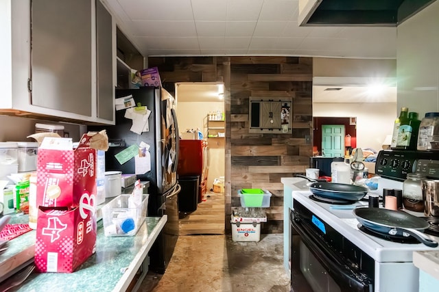 kitchen with wooden walls, concrete floors, and range