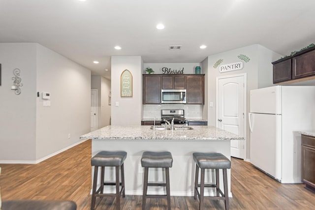 kitchen featuring dark brown cabinets, stainless steel appliances, a kitchen breakfast bar, and visible vents