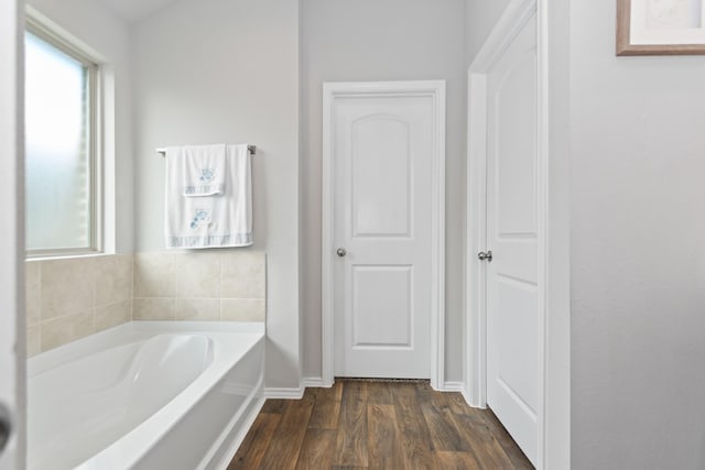 full bathroom with plenty of natural light, baseboards, a garden tub, and wood finished floors