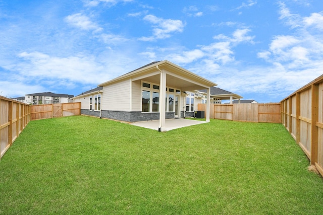 rear view of house with a fenced backyard, a lawn, and a patio