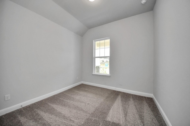 spare room featuring lofted ceiling, carpet flooring, and baseboards