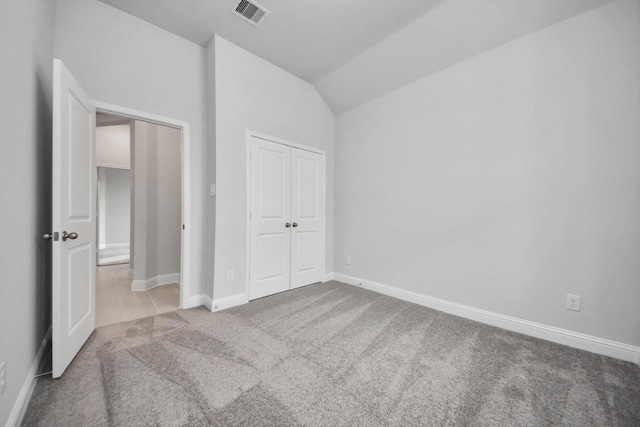 unfurnished bedroom featuring visible vents, baseboards, vaulted ceiling, a closet, and carpet