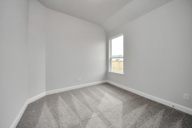 spare room featuring lofted ceiling, carpet flooring, and baseboards