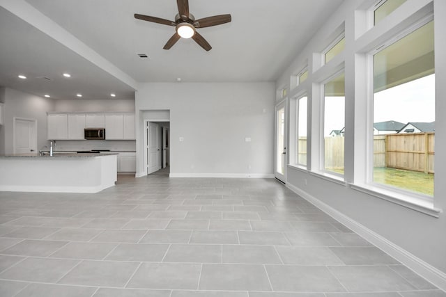 unfurnished living room featuring recessed lighting, visible vents, ceiling fan, a sink, and baseboards