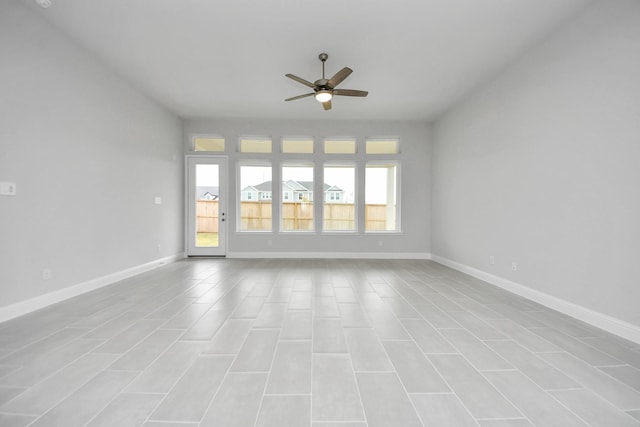 empty room with ceiling fan and baseboards