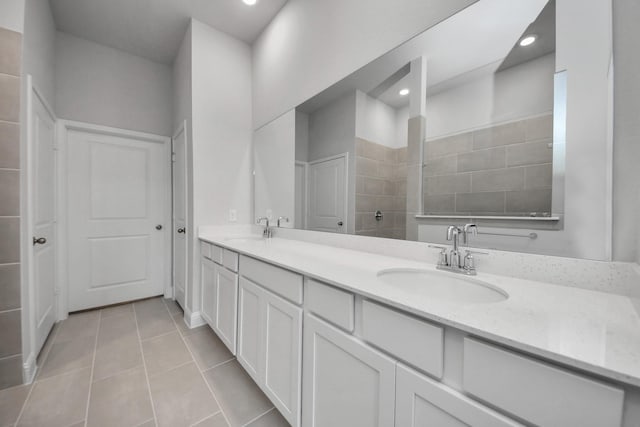 full bathroom featuring double vanity, a sink, a tile shower, and tile patterned floors