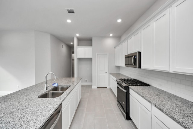 kitchen featuring visible vents, decorative backsplash, appliances with stainless steel finishes, white cabinetry, and a sink