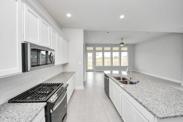 kitchen with recessed lighting, a sink, open floor plan, appliances with stainless steel finishes, and tasteful backsplash