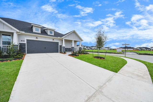 view of front of house featuring covered porch, board and batten siding, stone siding, driveway, and a front lawn