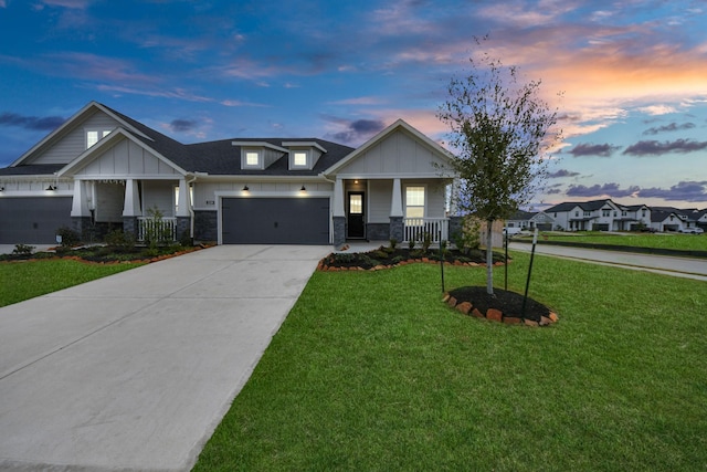 craftsman-style home with covered porch, concrete driveway, board and batten siding, and a lawn