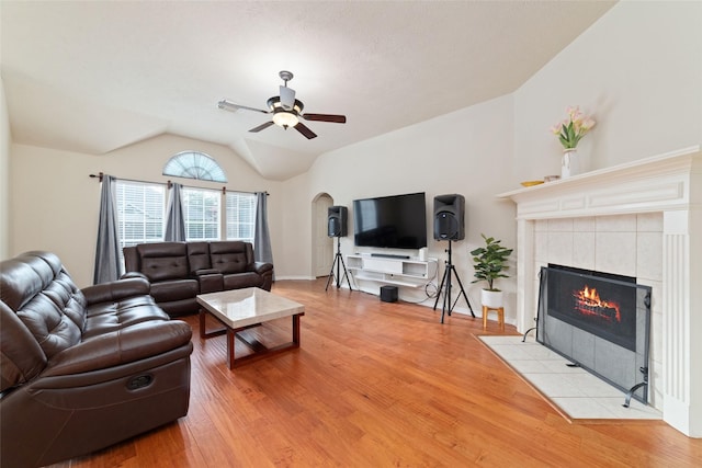 living room featuring a fireplace, light hardwood / wood-style floors, ceiling fan, and lofted ceiling