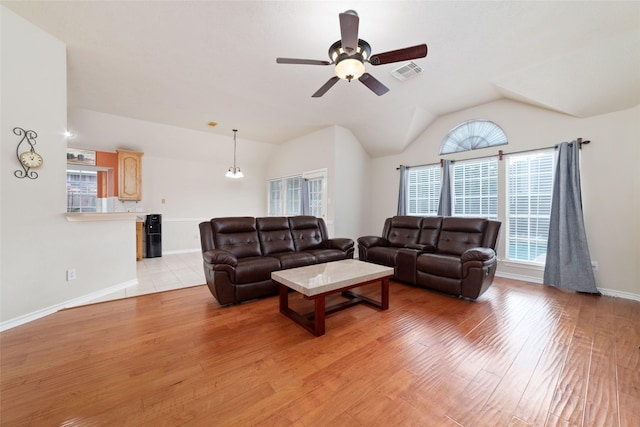 living room with ceiling fan with notable chandelier, light wood-type flooring, and lofted ceiling