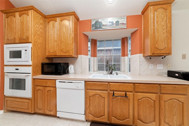 kitchen featuring white appliances, sink, light tile patterned floors, a textured ceiling, and tasteful backsplash